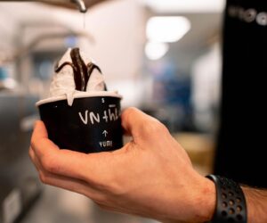 Hand holding a cup of Chill-N vanilla ice cream topped with chocolate sauce