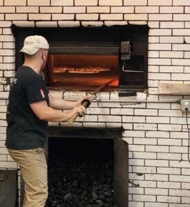 Frank Pepe Pizzeria chef putting a pizza pie into the oven