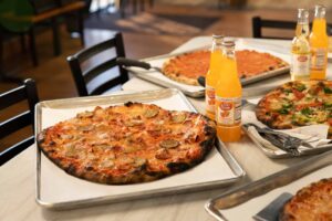 Pizza pie with bottles of orange soda at Frank Pepe Pizzeria